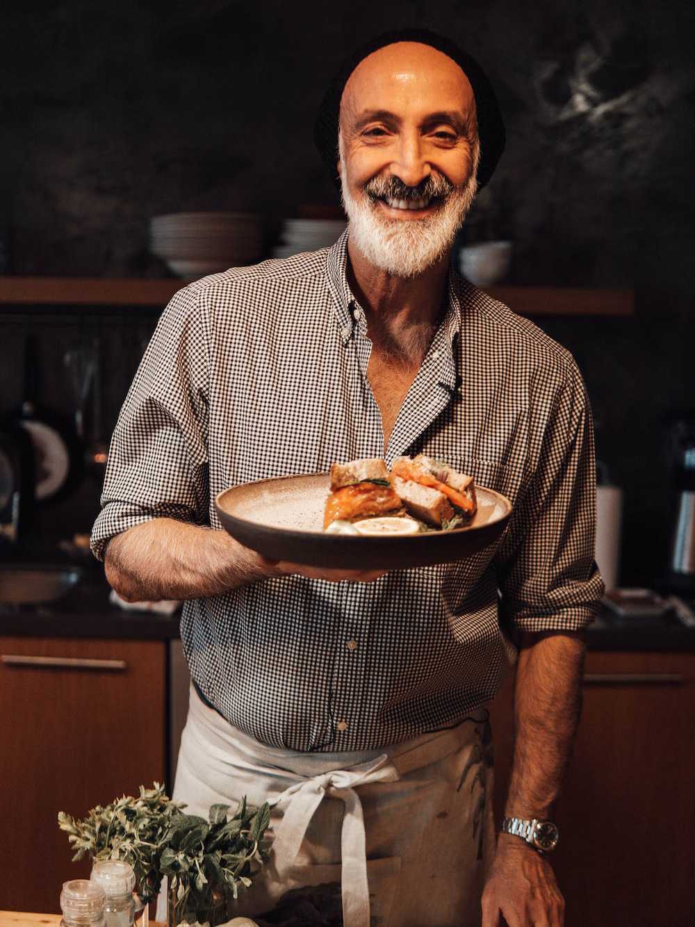 Messy Sandwich Company founder Abu Dhabi holding a plate of food in a kitchen.