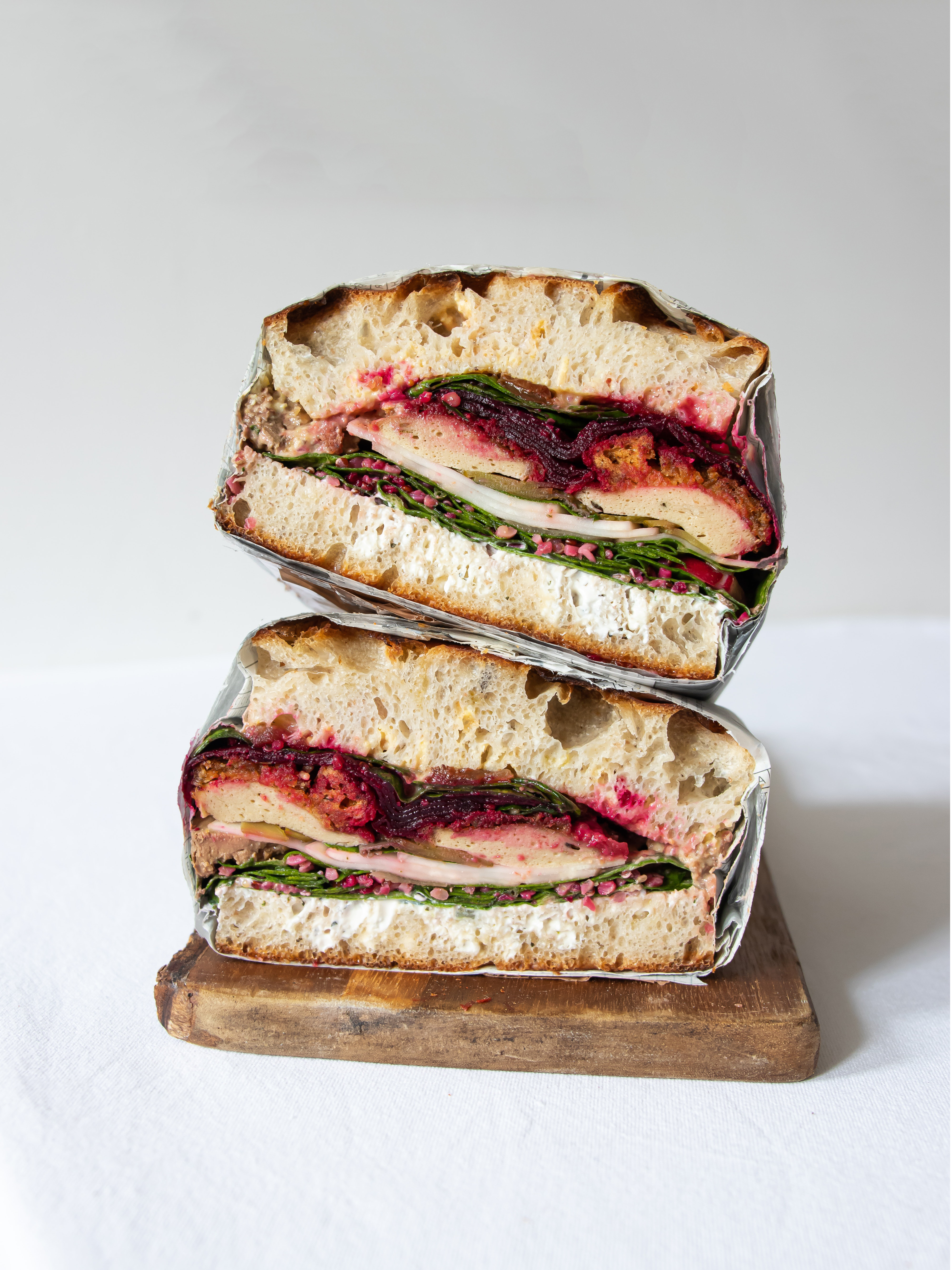 Turkey sandwich with cranberries and spinach on a wooden cutting board.